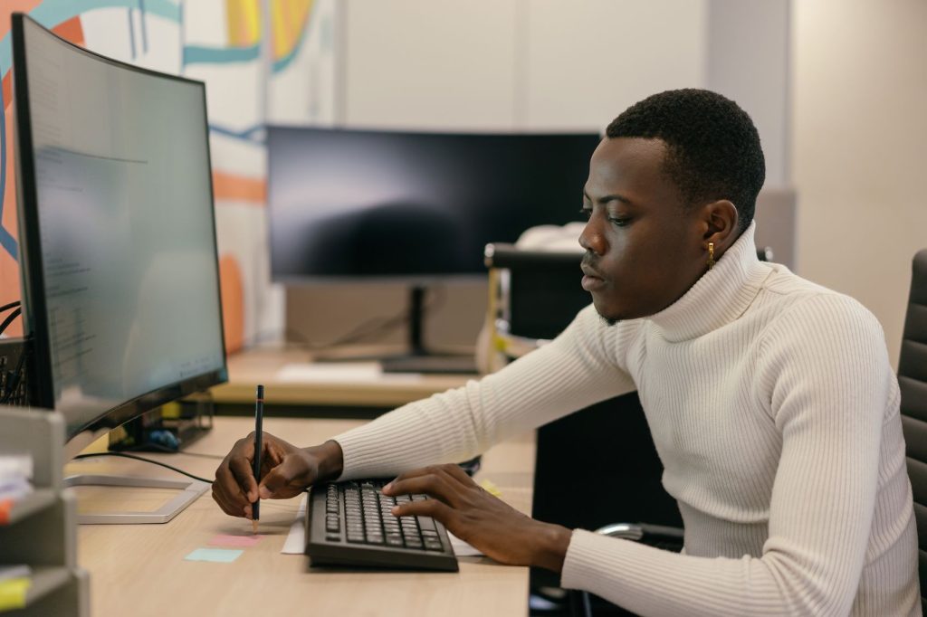 A software engineer writing code at a desk in an office