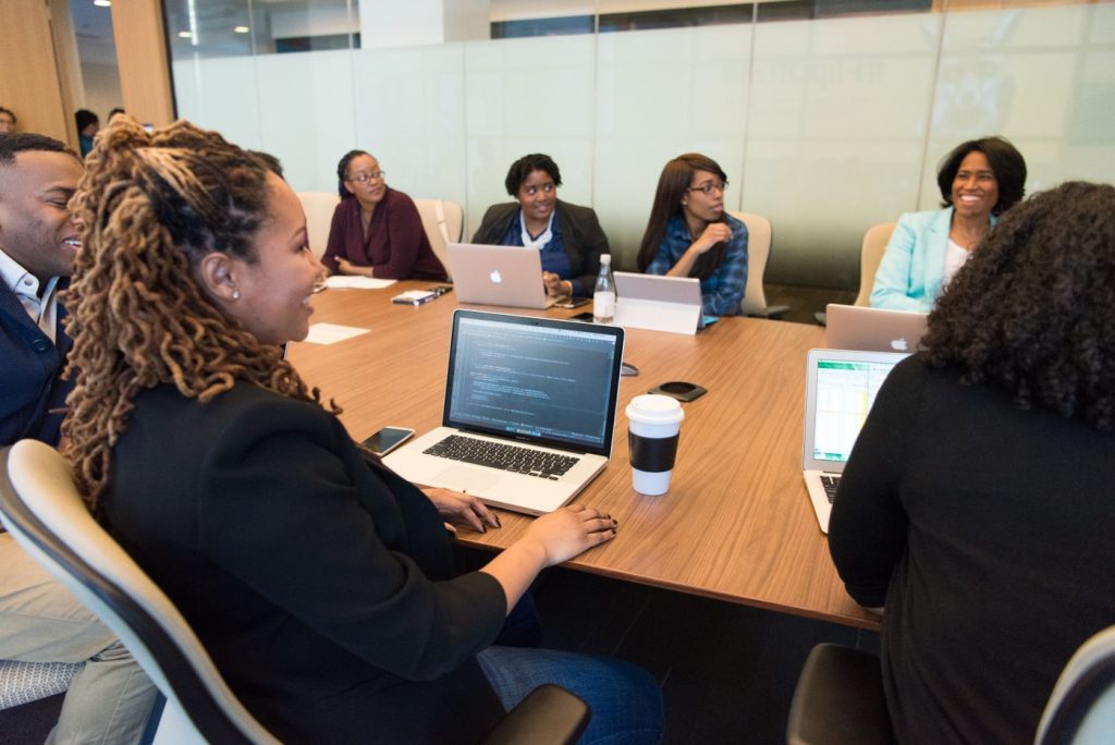 A team meeting around a boardroom table with laptops