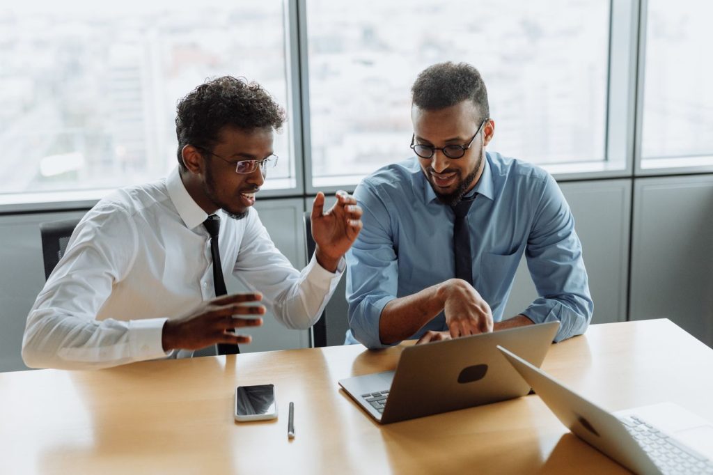 Two colleagues working together over laptops in an office